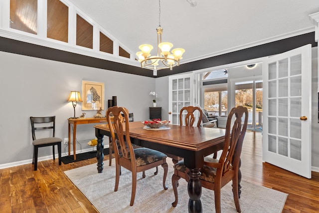 dining area with hardwood / wood-style flooring, lofted ceiling, and a chandelier