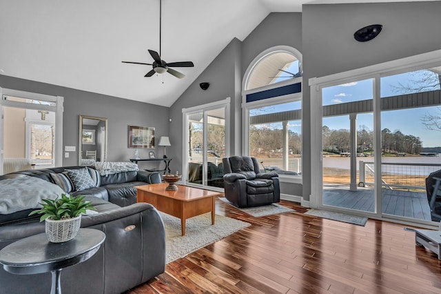 living room with hardwood / wood-style flooring, high vaulted ceiling, ceiling fan, and a water view