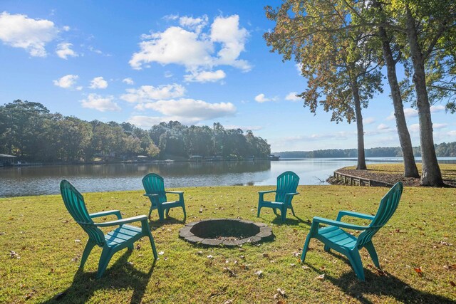 view of home's community featuring a water view, a lawn, and an outdoor fire pit