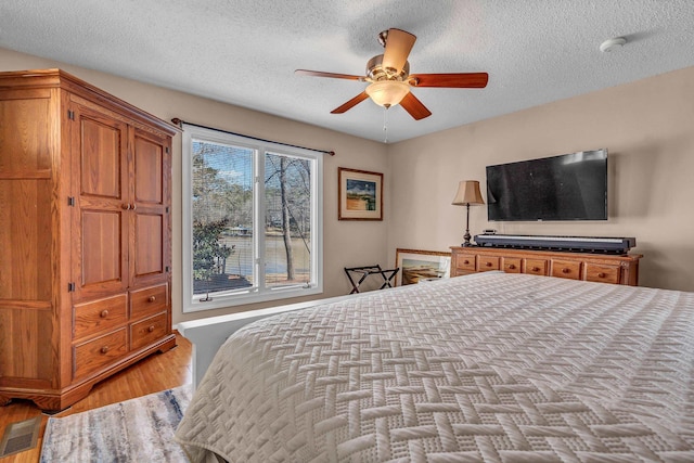 bedroom featuring ceiling fan, light hardwood / wood-style flooring, and a textured ceiling