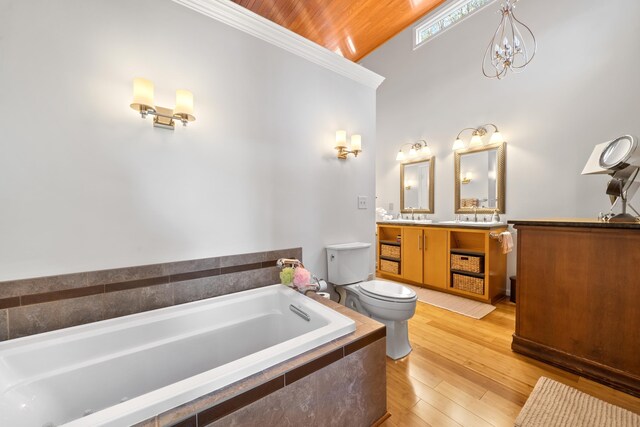 bathroom featuring toilet, wood-type flooring, vanity, a notable chandelier, and tiled bath