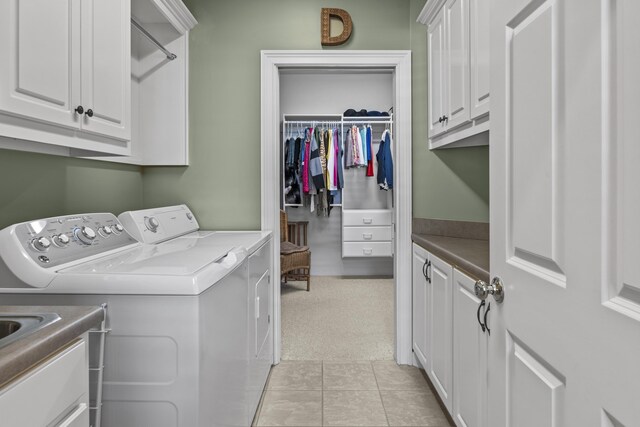 washroom with light tile patterned floors, washing machine and dryer, and cabinets