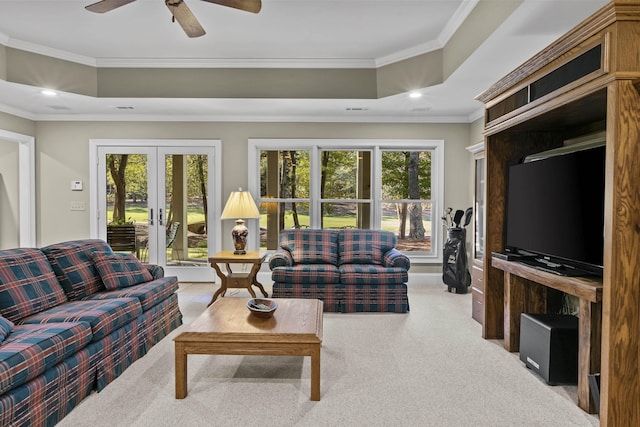 carpeted living room featuring crown molding, a tray ceiling, french doors, and ceiling fan