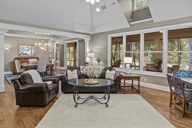 living room with ornate columns, wood-type flooring, a healthy amount of sunlight, and a chandelier