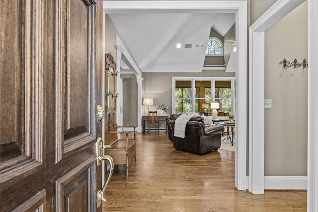 foyer with high vaulted ceiling, hardwood / wood-style flooring, and decorative columns