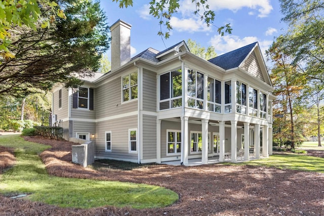 rear view of property featuring a yard and a sunroom