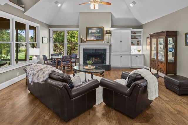 living room with wood-type flooring, high vaulted ceiling, ceiling fan, and a fireplace