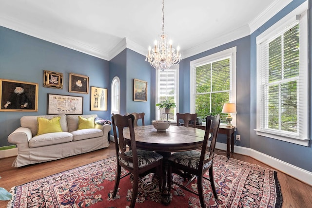 dining space featuring crown molding, wood finished floors, an inviting chandelier, and baseboards