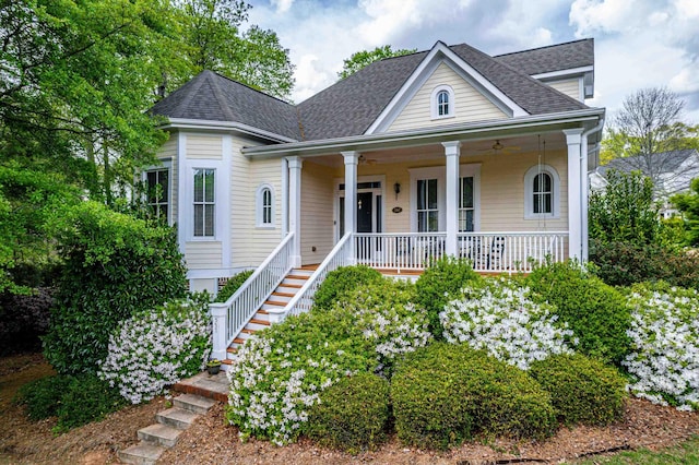 view of front of house featuring roof with shingles, covered porch, and stairway