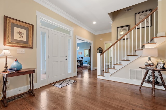 entrance foyer with crown molding, wood finished floors, visible vents, and stairs