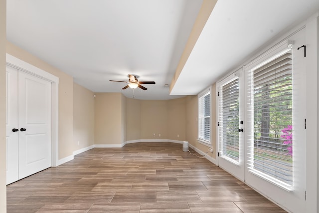 unfurnished room featuring light wood-style flooring, baseboards, and a ceiling fan