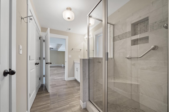 full bath featuring baseboards, a shower stall, vanity, and wood finished floors