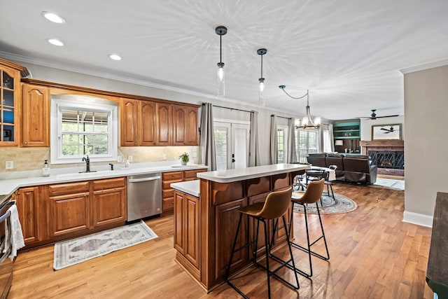 kitchen with a kitchen bar, sink, hanging light fixtures, stainless steel dishwasher, and a kitchen island