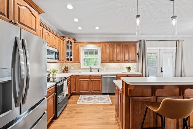 kitchen with pendant lighting, sink, appliances with stainless steel finishes, a kitchen breakfast bar, and ornamental molding