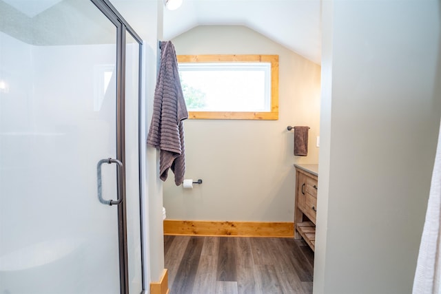 bathroom featuring lofted ceiling, hardwood / wood-style flooring, a shower with door, vanity, and toilet