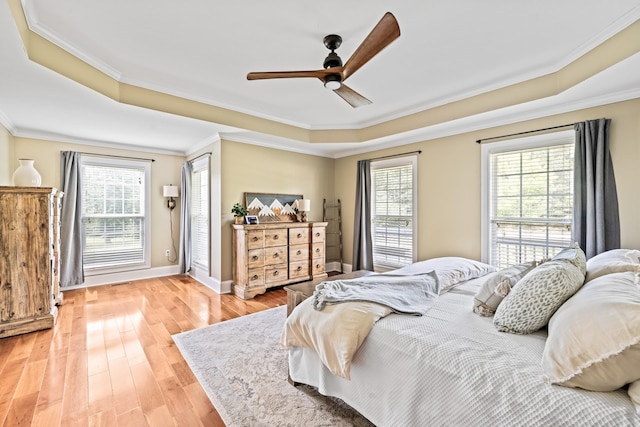 bedroom featuring a raised ceiling, ornamental molding, hardwood / wood-style floors, and multiple windows