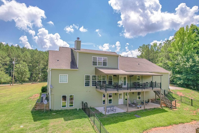 rear view of house featuring a deck, a patio area, and a lawn