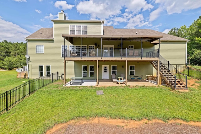 back of property featuring a wooden deck, a patio area, and a lawn