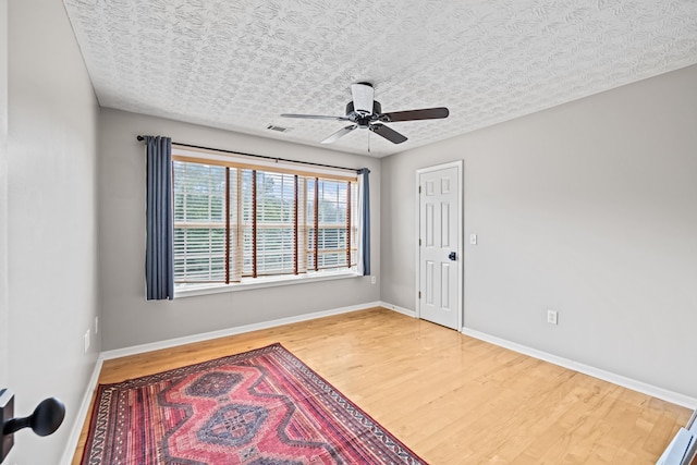 empty room with hardwood / wood-style floors, a textured ceiling, and ceiling fan