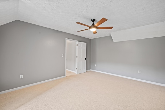 carpeted spare room with ceiling fan, lofted ceiling, and a textured ceiling