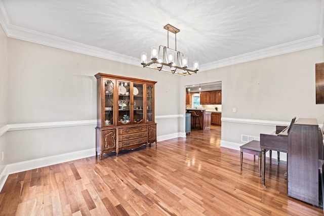 dining room with an inviting chandelier, ornamental molding, and light hardwood / wood-style floors