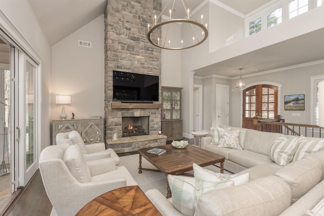 living room featuring hardwood / wood-style floors, a fireplace, ornamental molding, a notable chandelier, and french doors