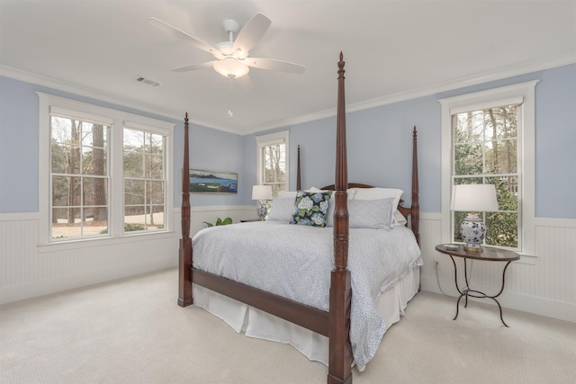 carpeted bedroom with ceiling fan, ornamental molding, and multiple windows