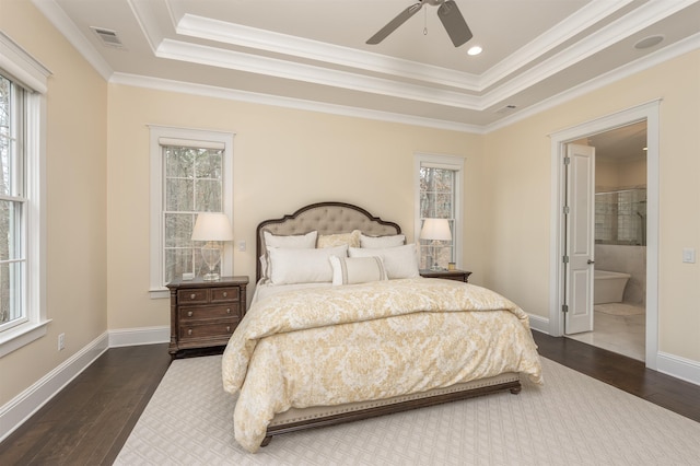 bedroom with ensuite bath, ornamental molding, dark hardwood / wood-style flooring, and a raised ceiling