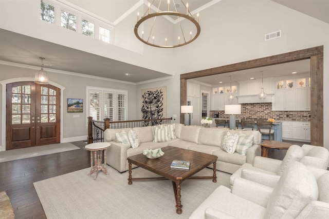 living room featuring french doors, dark hardwood / wood-style flooring, a chandelier, and crown molding