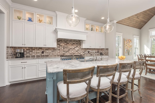 kitchen featuring white cabinetry, an island with sink, and hanging light fixtures