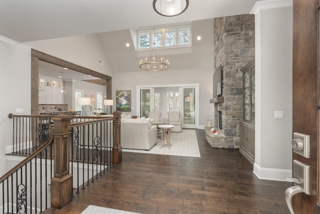 living room featuring dark wood-type flooring, a fireplace, high vaulted ceiling, and a notable chandelier