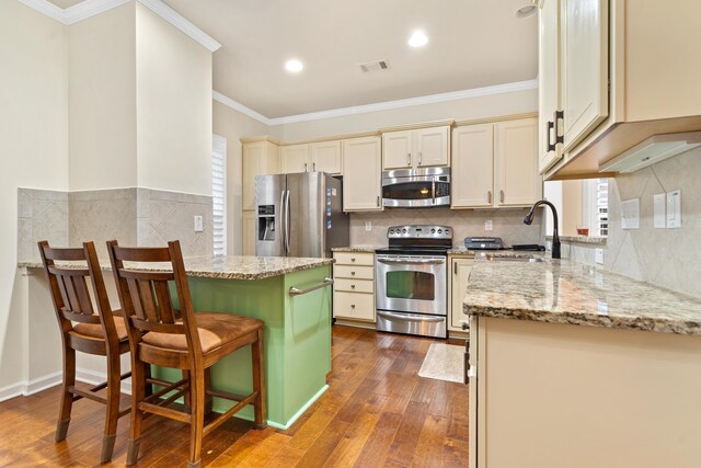 kitchen with sink, light stone counters, a center island, a kitchen breakfast bar, and stainless steel appliances