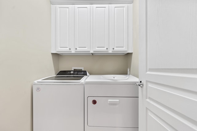 clothes washing area featuring cabinets and washer and dryer