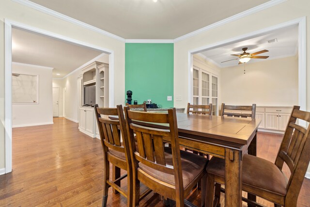 dining area with crown molding, ceiling fan, and light wood-type flooring