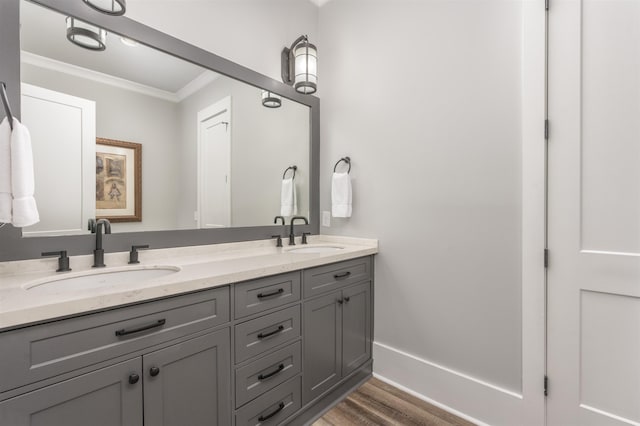 full bath featuring double vanity, ornamental molding, a sink, and wood finished floors