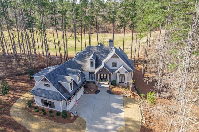 view of front of property with driveway, a shingled roof, and a chimney