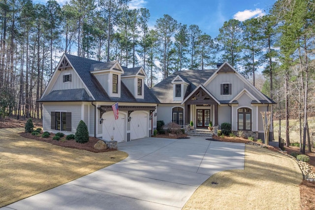 view of front facade with a shingled roof, concrete driveway, an attached garage, french doors, and board and batten siding