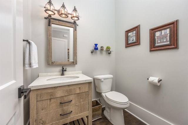 half bath with toilet, baseboards, and vanity