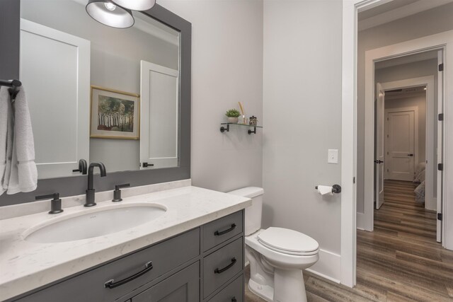 bathroom with baseboards, vanity, toilet, and wood finished floors