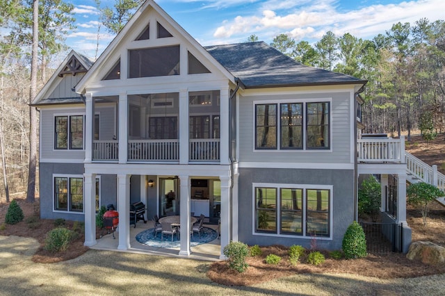 rear view of house with a patio, stairway, a sunroom, and stucco siding