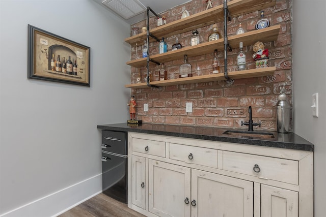 bar featuring baseboards, indoor wet bar, a sink, and wood finished floors