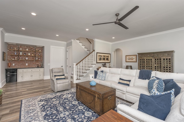 living room featuring arched walkways, ornamental molding, stairway, and wood finished floors