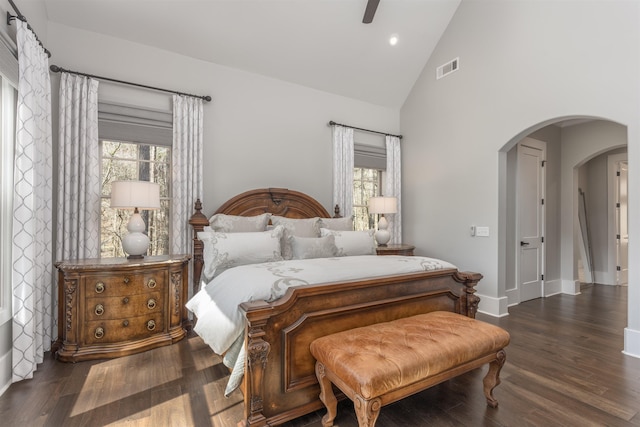 bedroom with multiple windows, arched walkways, and wood finished floors