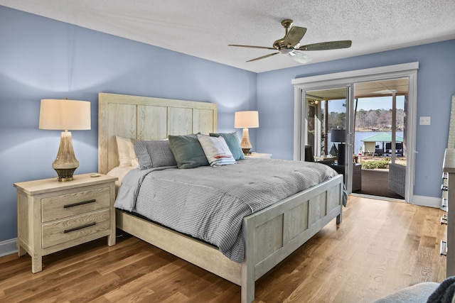 bedroom featuring baseboards, wood finished floors, a textured ceiling, and access to exterior