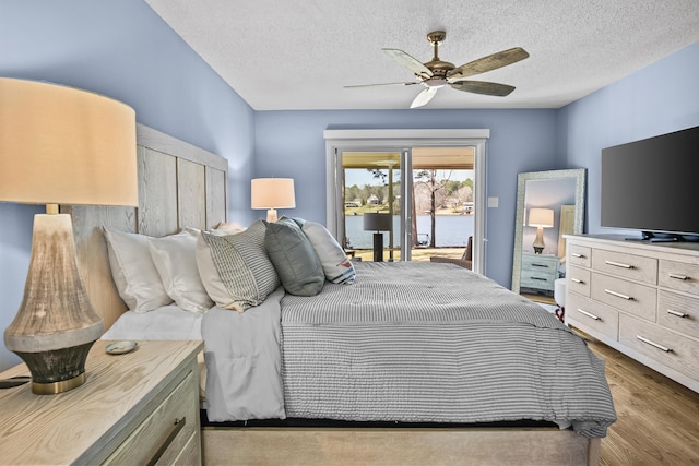 bedroom with ceiling fan, access to exterior, wood finished floors, and a textured ceiling