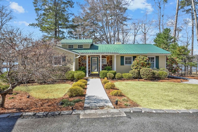 view of front of home featuring metal roof, a chimney, and a front lawn