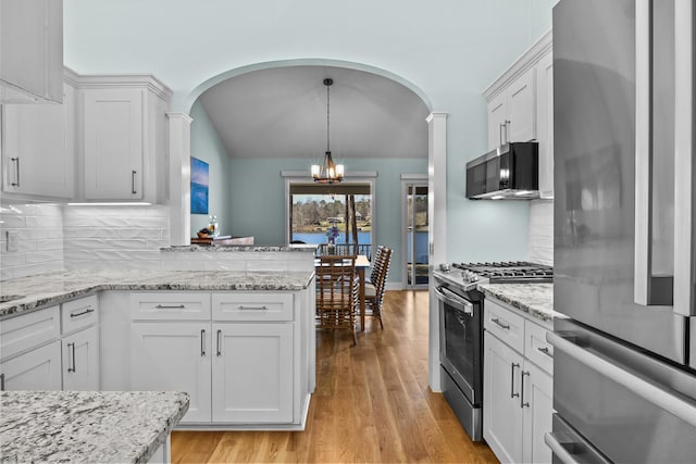 kitchen with a chandelier, light wood-type flooring, arched walkways, white cabinets, and stainless steel appliances