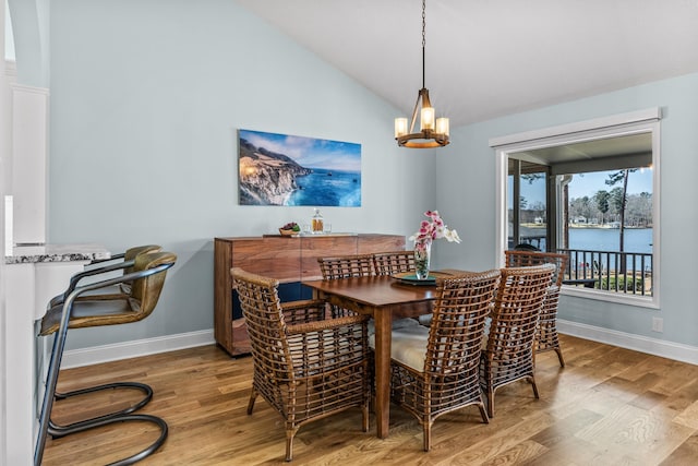 dining room featuring an inviting chandelier, wood finished floors, baseboards, and lofted ceiling