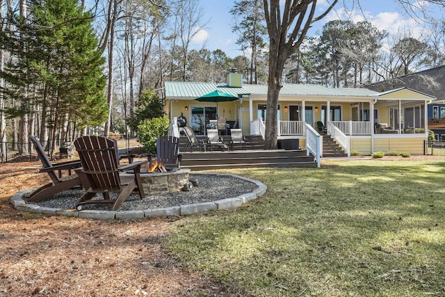 rear view of house featuring metal roof, a lawn, a chimney, and an outdoor fire pit