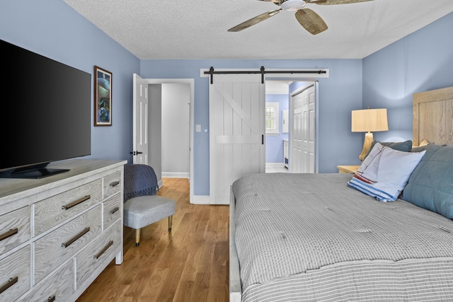 bedroom featuring a closet, a textured ceiling, a barn door, and wood finished floors